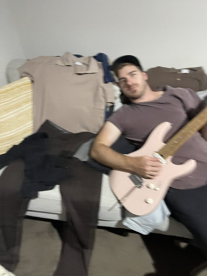 Jye on the couch with a pink electric guitar