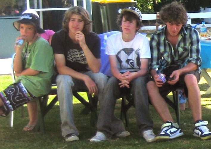 Four teenagers sitting on camp chairs in a backyard